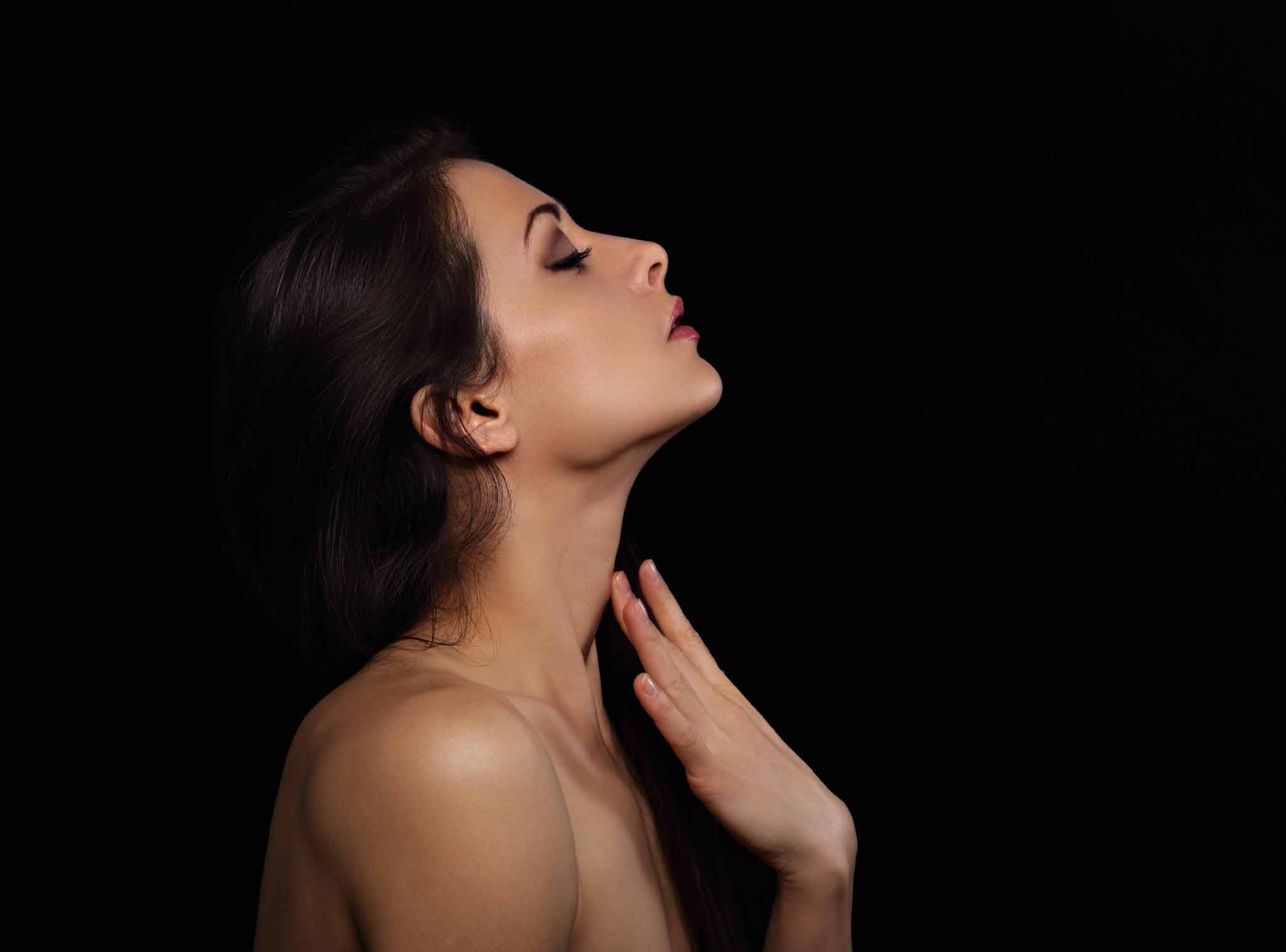 Beautiful makeup sexy woman touching the fingers elegant healthy neck skin wirh nude back and shoulder on black background with empty copy space. Closeup profile view portrait. Art.Expression.